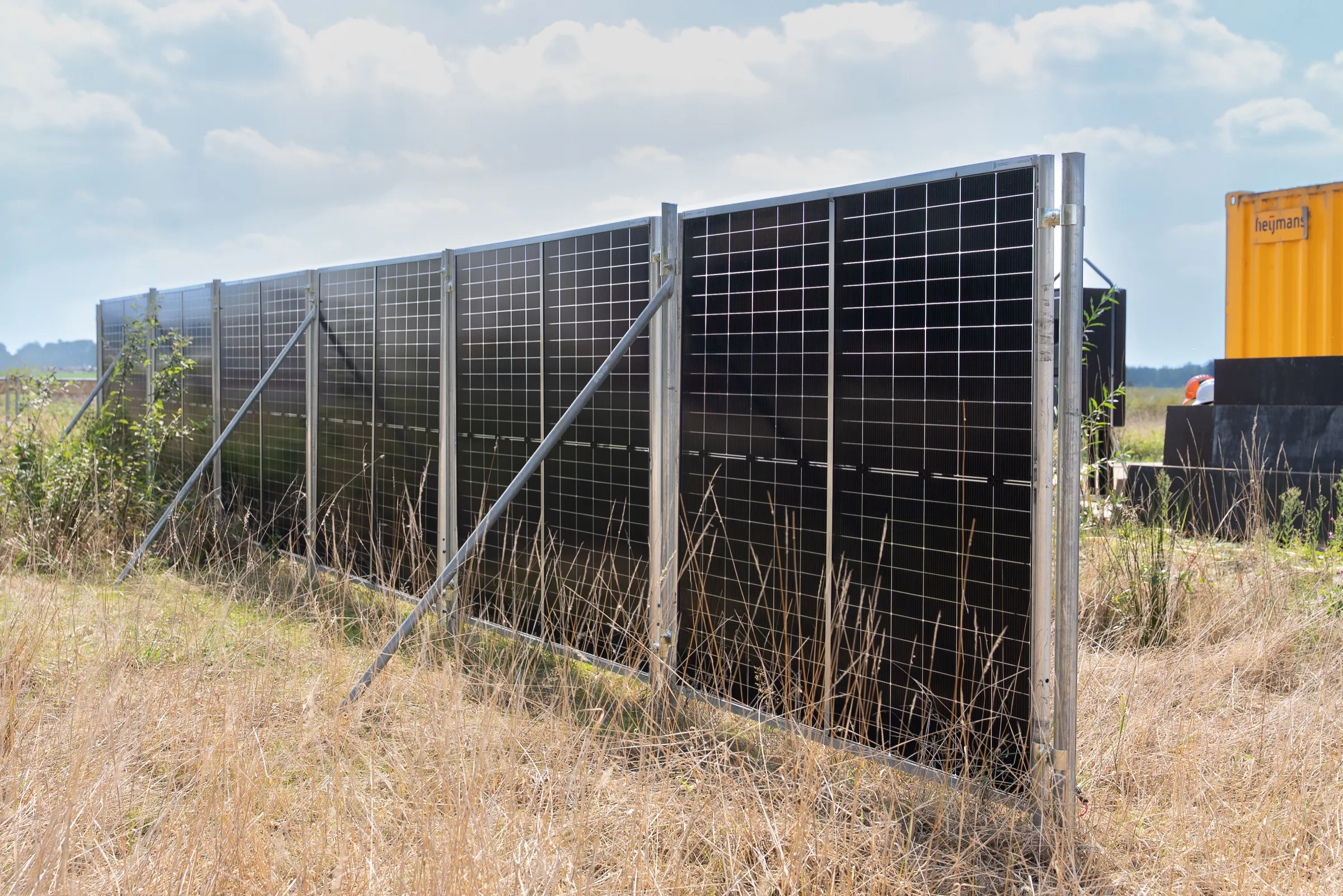 Zonnebouwhek voor een gele container op een bouwterrein
