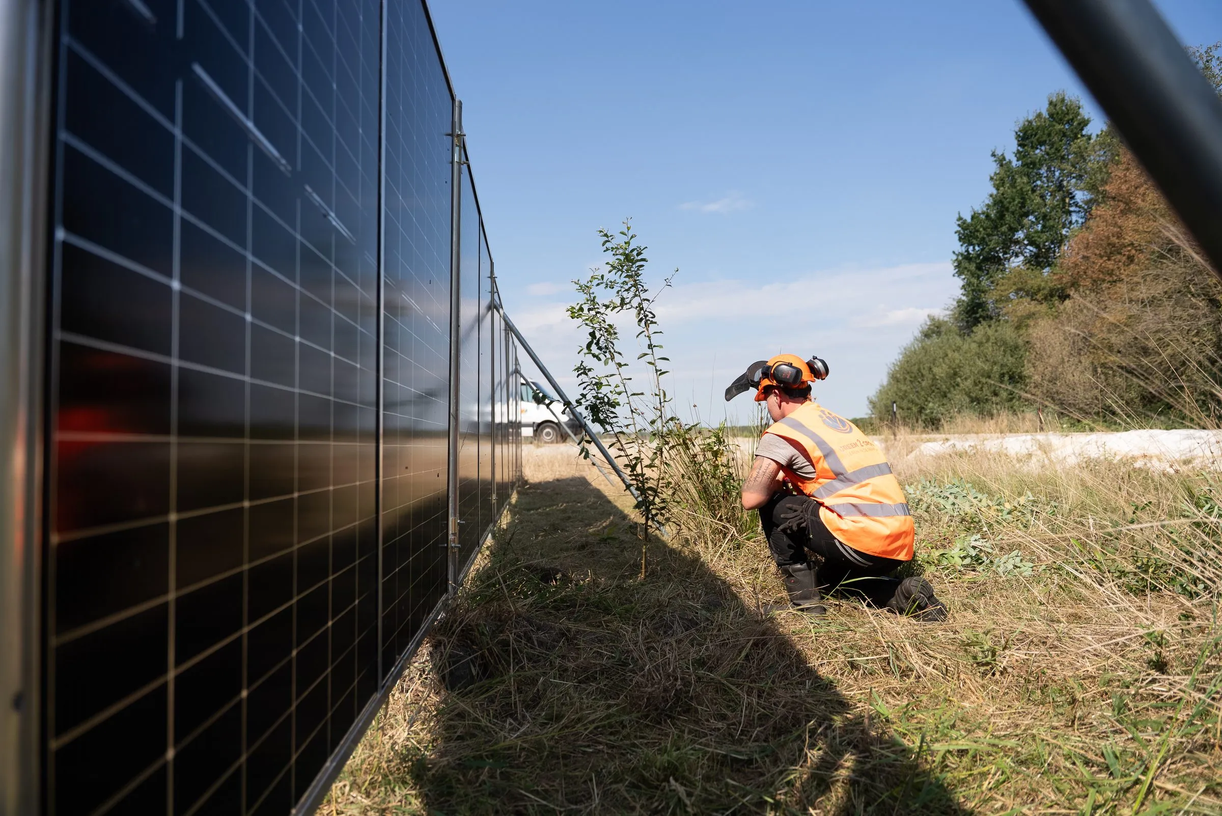 Lange rij zonnebouwhekken, laag vanaf de grond gefotografeerd, met een medewerker op de achtergrond