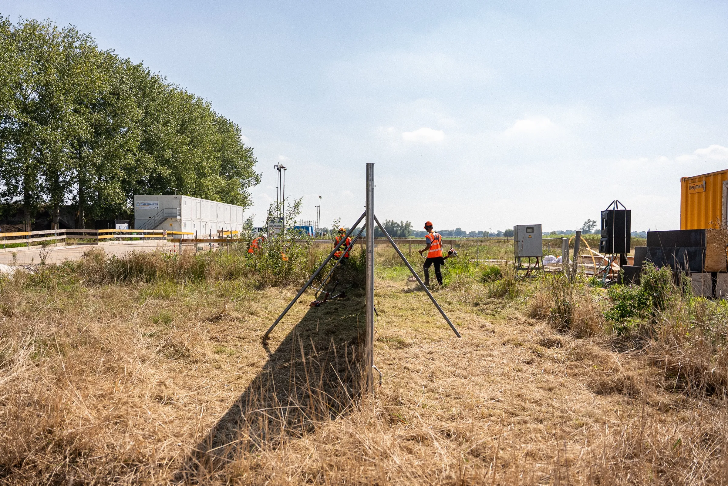 Rij zonnebouwhekken met schoren op een bouwterrein met bomen op de achtergrond