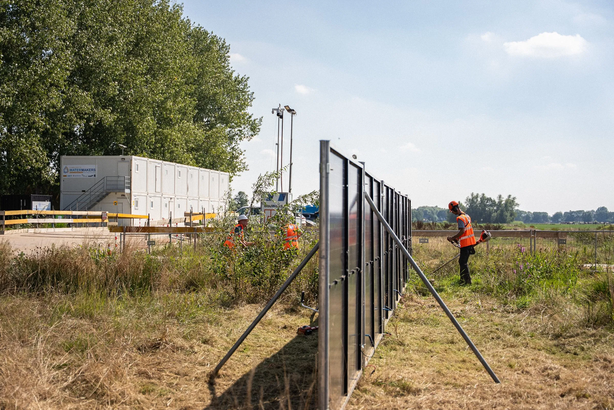 Zijaanzicht van een rij zonnebouwhekken met schoren op een bouwterrein