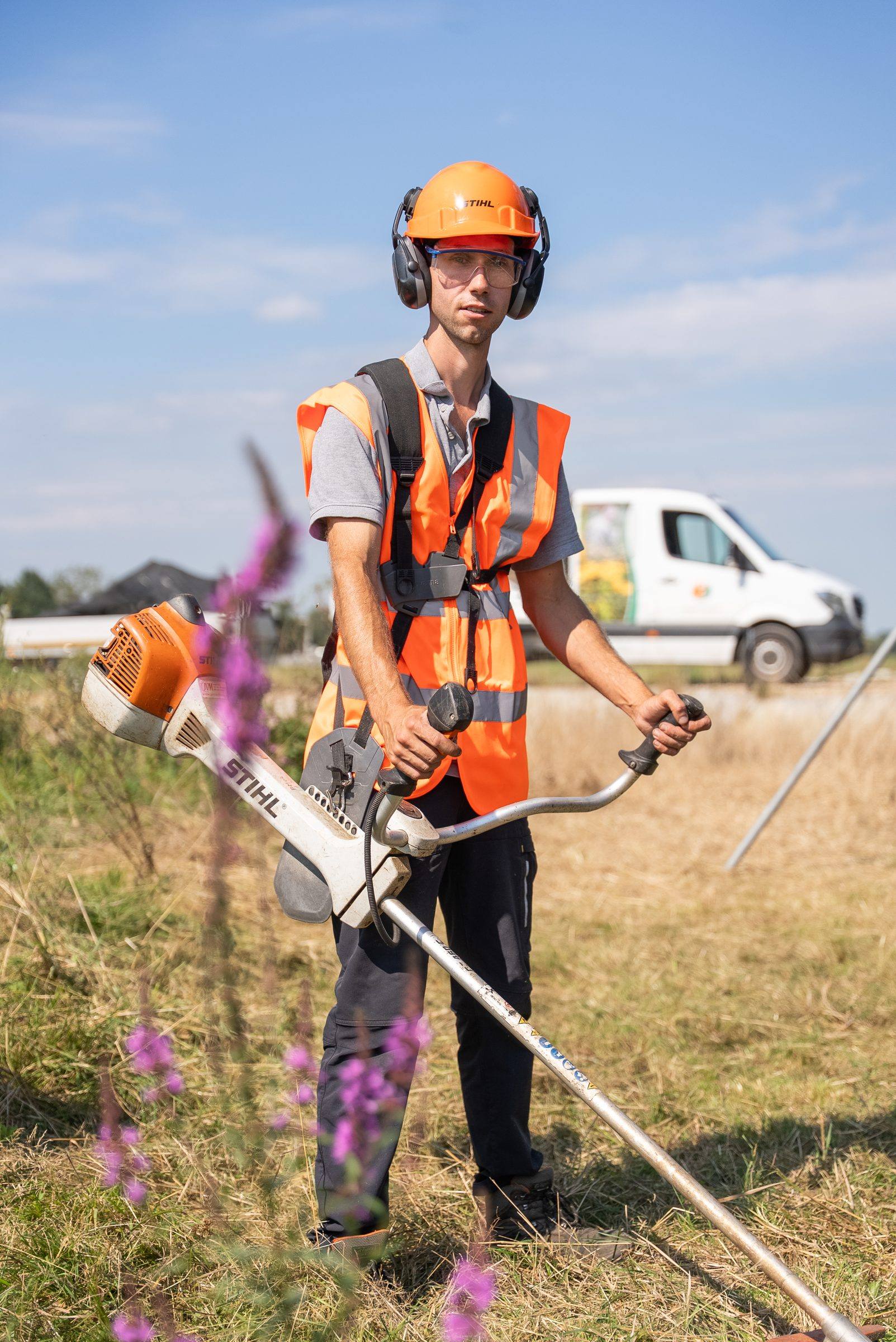 Medewerker met bosmaaier bij de hekken