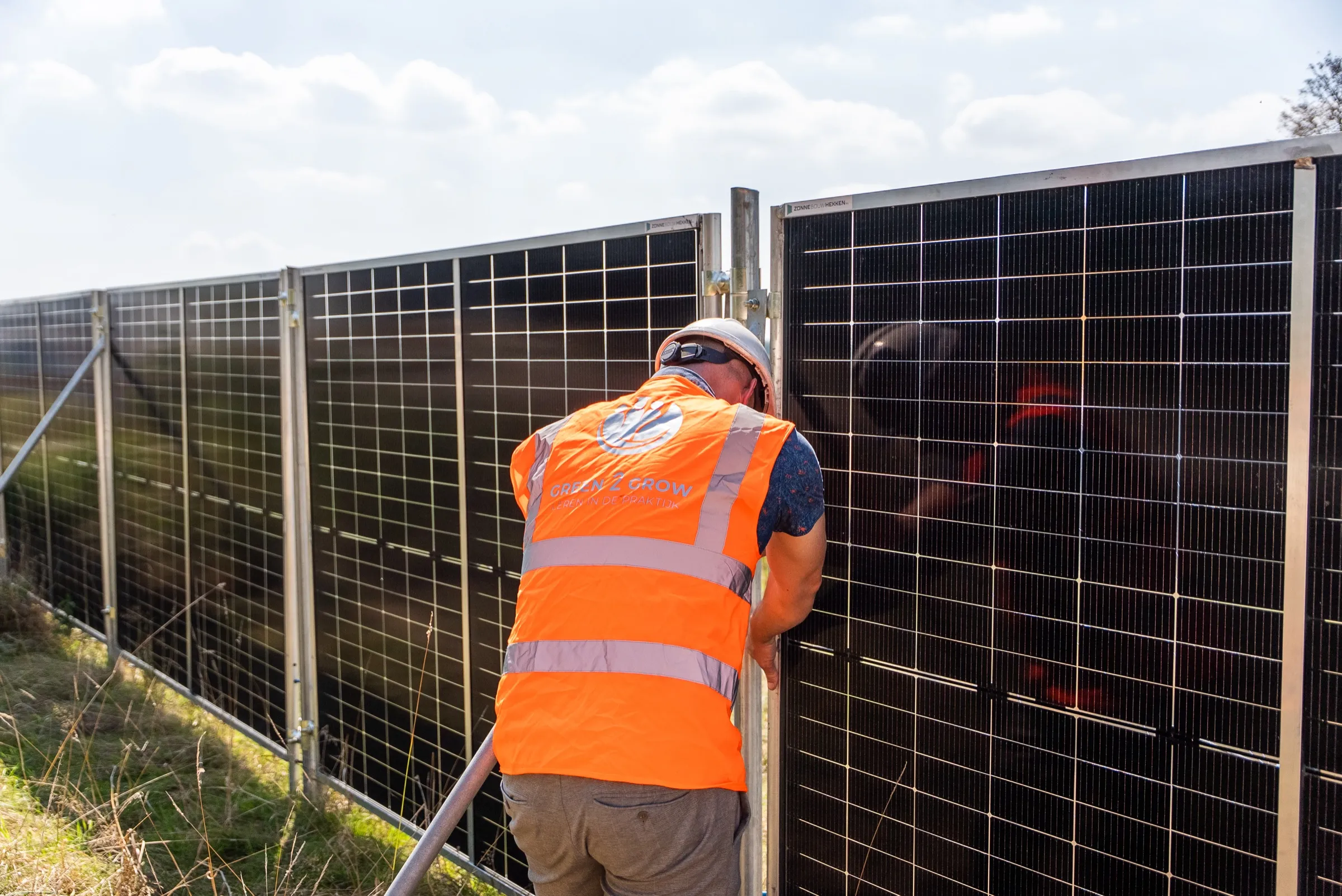Monteur plaatst een zonnepaneel in het frame van een zonnebouwhek
