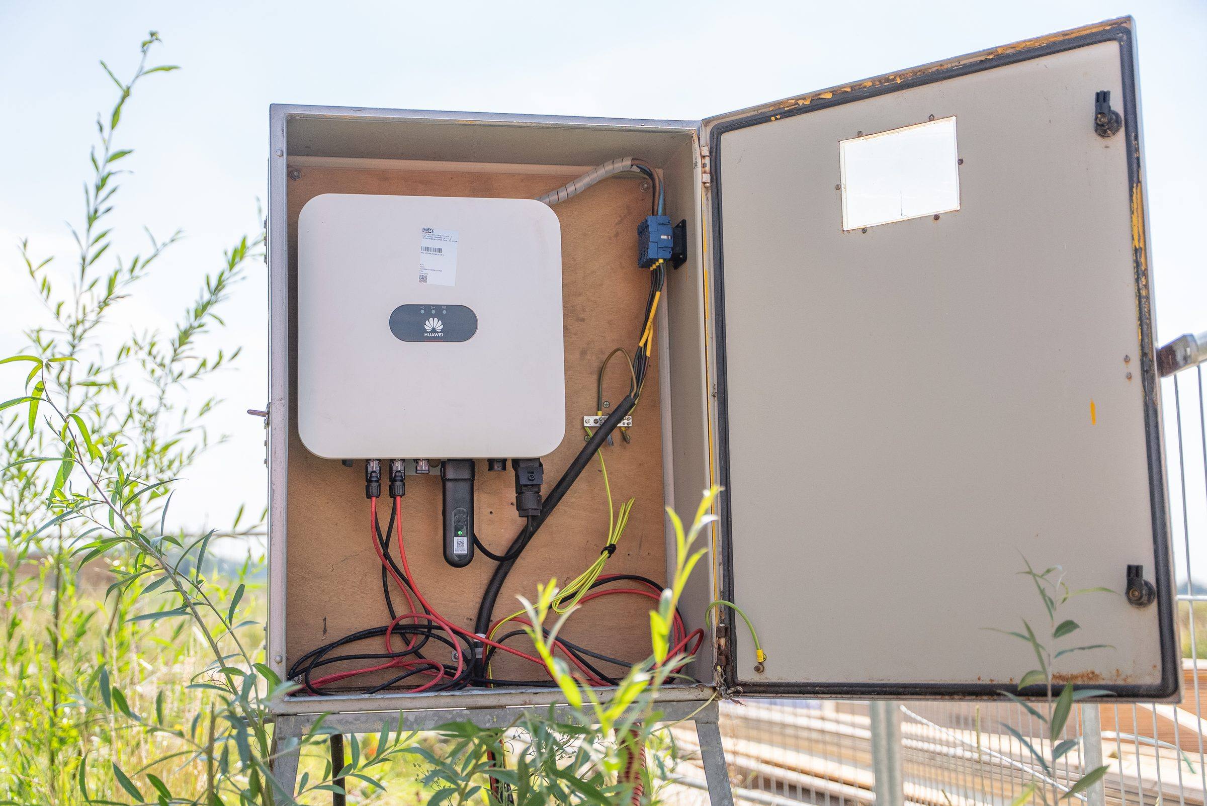 Geopende omvormerkast naast de zonnebouwhekken