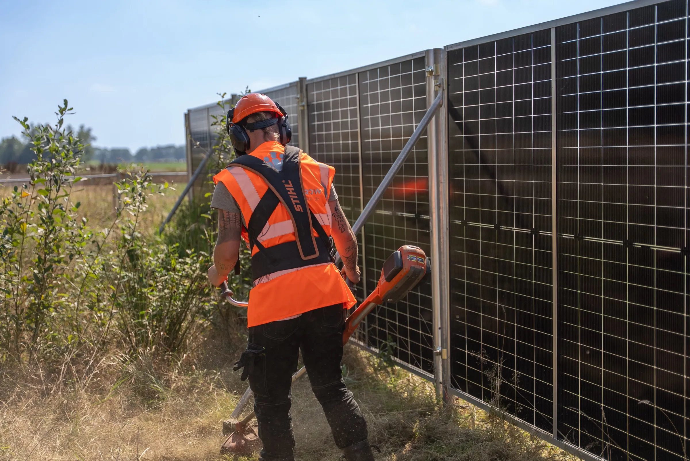 Medewerker van Green to Grow maait het gras langs de zonnebouwhekken