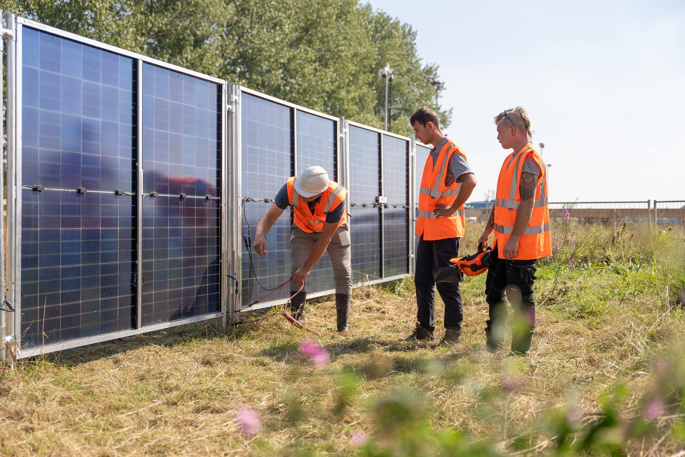 Leidinggevende legt twee medewerkers iets uit bij de zonnebouwhekken