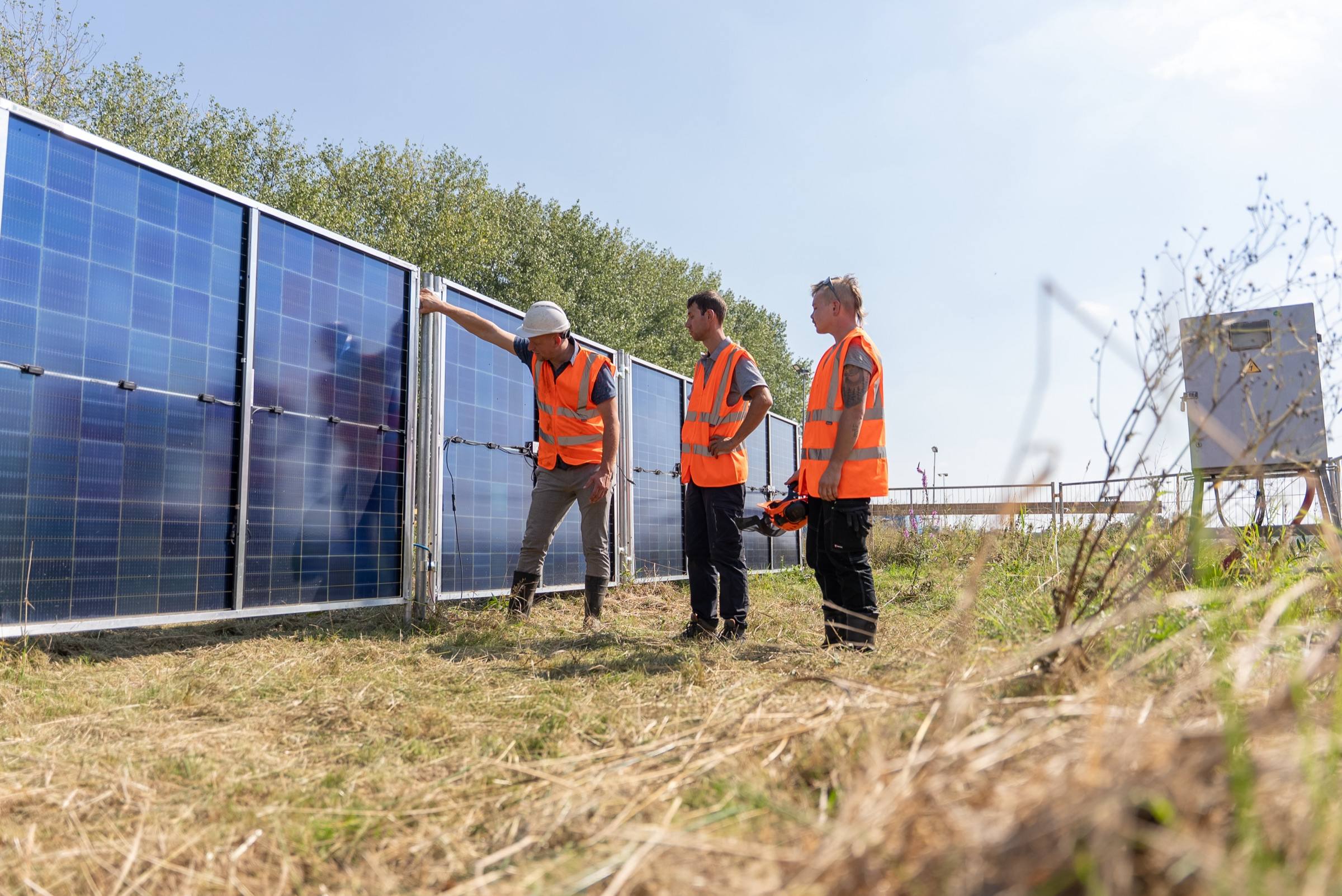 Drie medewerkers van Green to Grow in gesprek naast een lange rij zonnebouwhekken