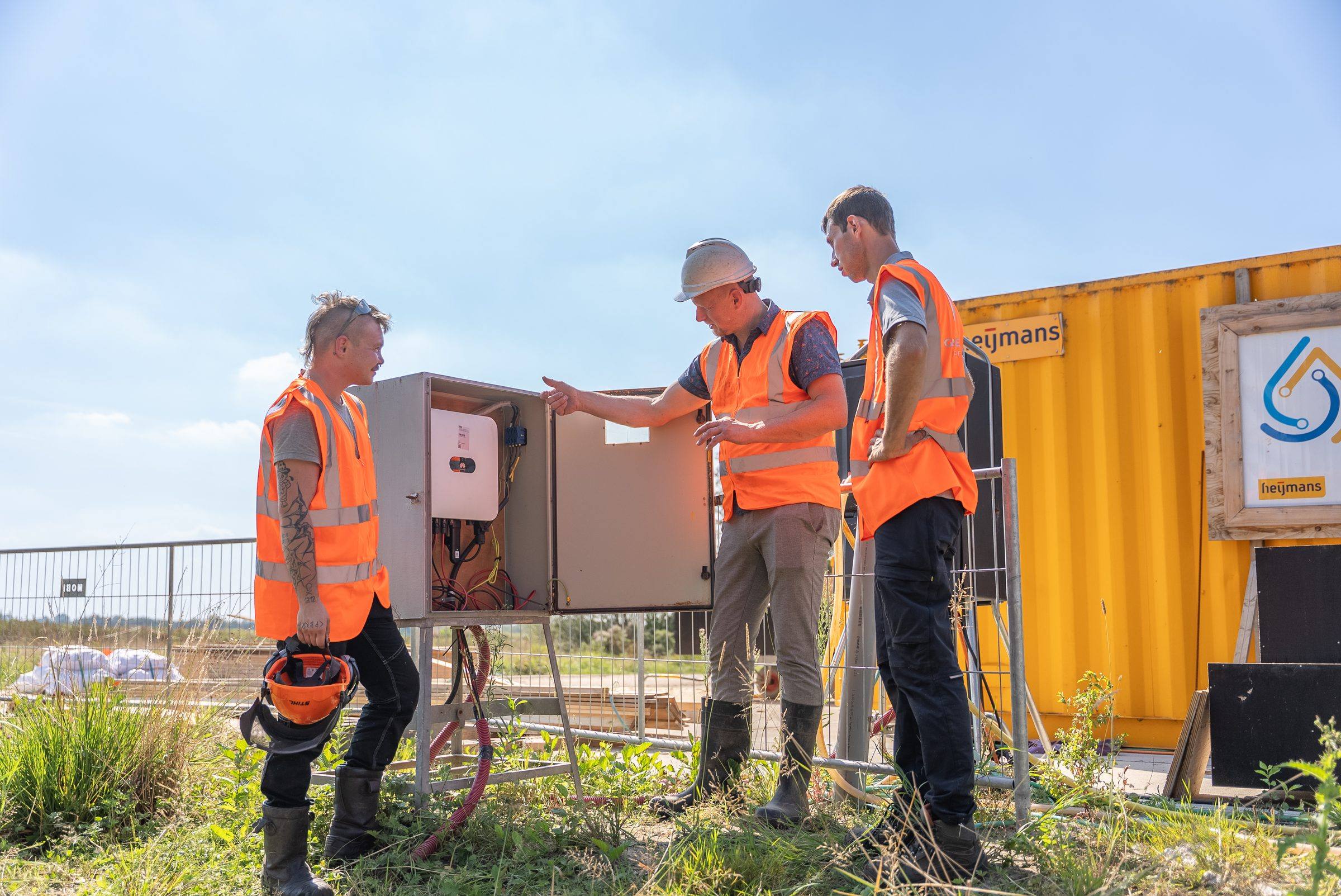 Drie medewerkers van Green to Grow bij de omvormerkast van de zonnebouwhekken
