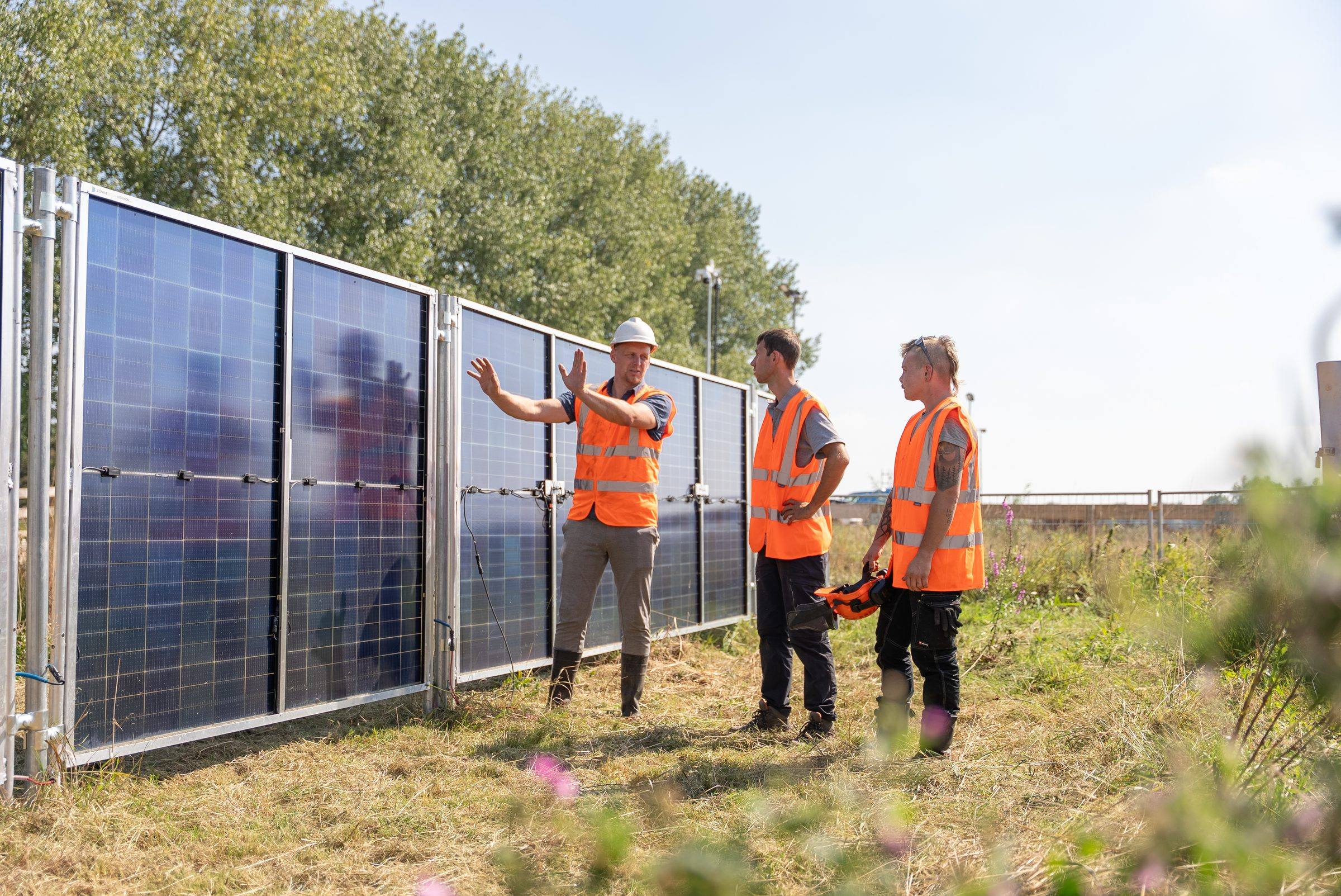 Drie medewerkers van Green to Grow in gesprek naast de zonnebouwhekken