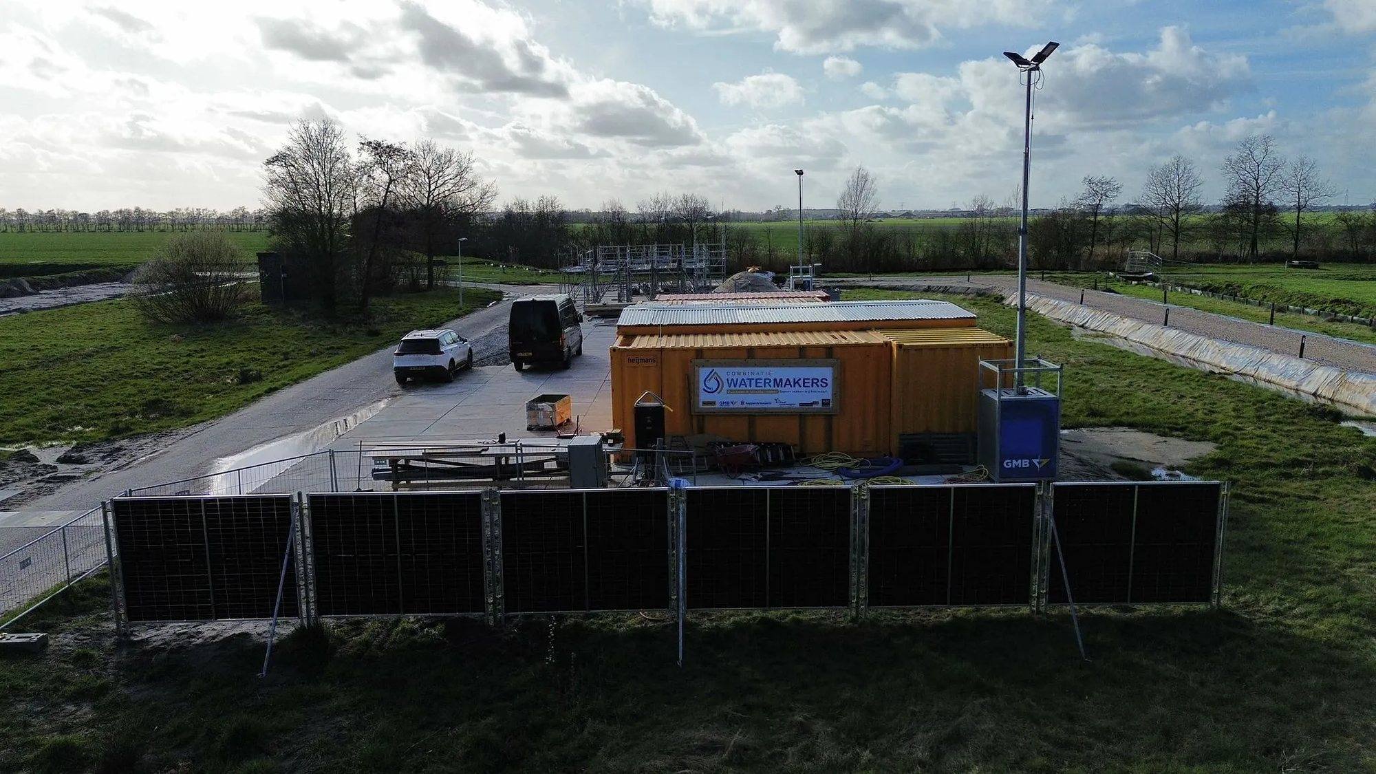 Luchtfoto van de bouwplaats van Combinatie Watermakers met de rij zonnebouwhekken