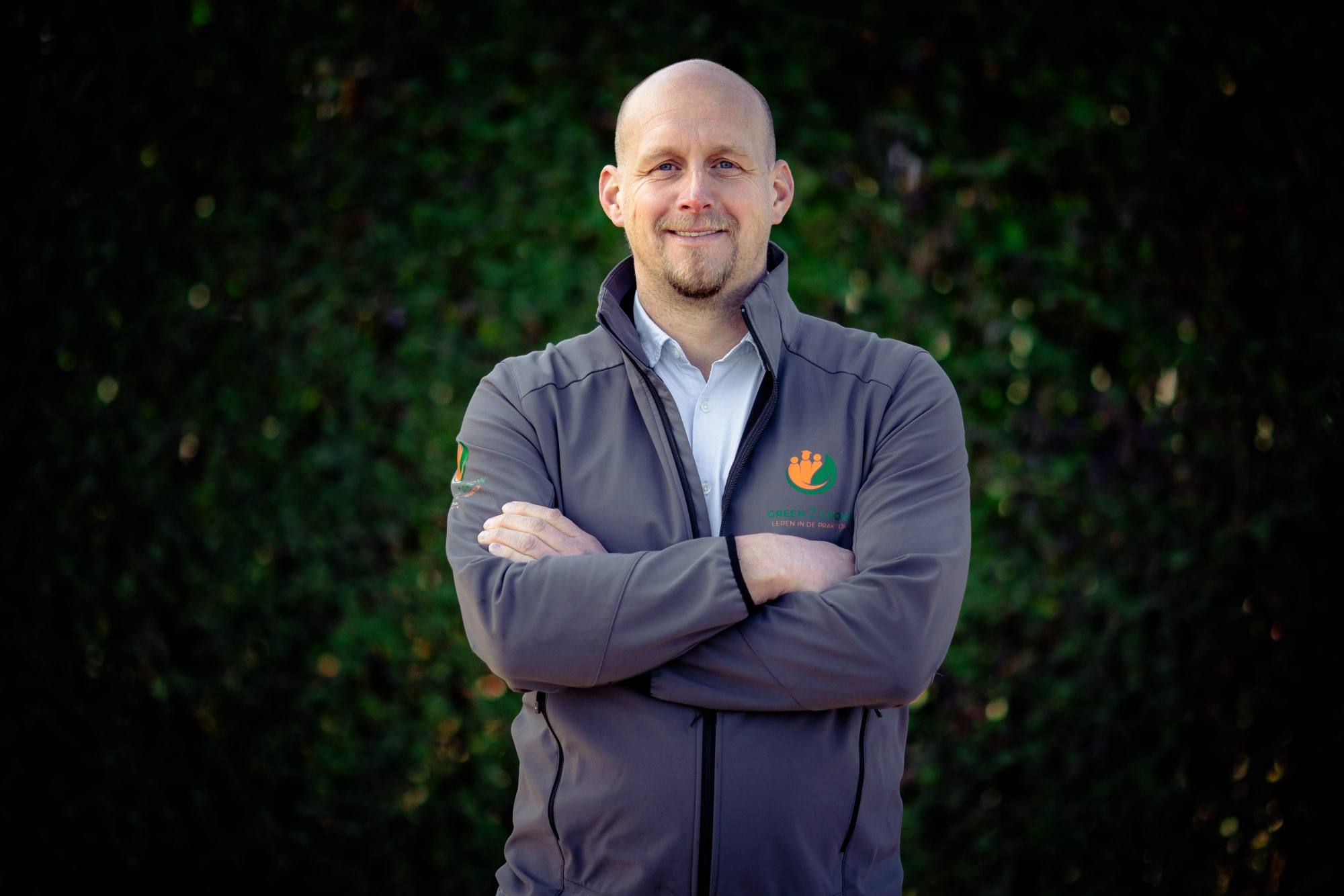 Wim van Vulpen, initiatiefnemer van Zonnebouwhekken, met de armen over elkaar voor een groene haag
